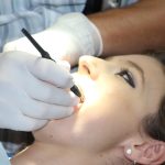 Stomatolog wykonuje zabieg leczenia zęba pacjentce w fotelu dentystycznym