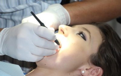 Stomatolog wykonuje zabieg leczenia zęba pacjentce w fotelu dentystycznym