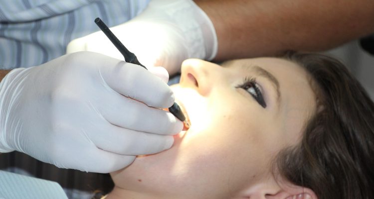 Stomatolog wykonuje zabieg leczenia zęba pacjentce w fotelu dentystycznym